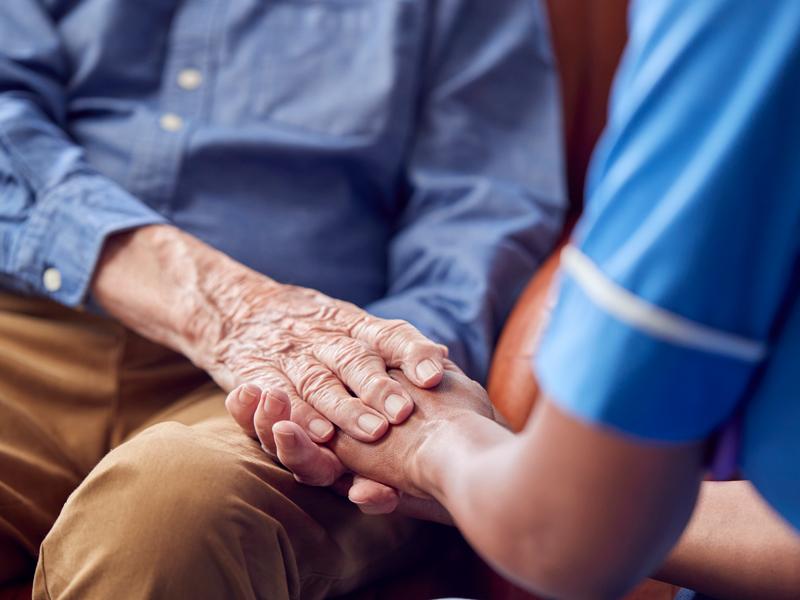 Carer and patient touching hands