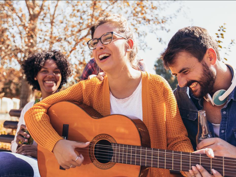 A student with a guitar surrounded by others smiling