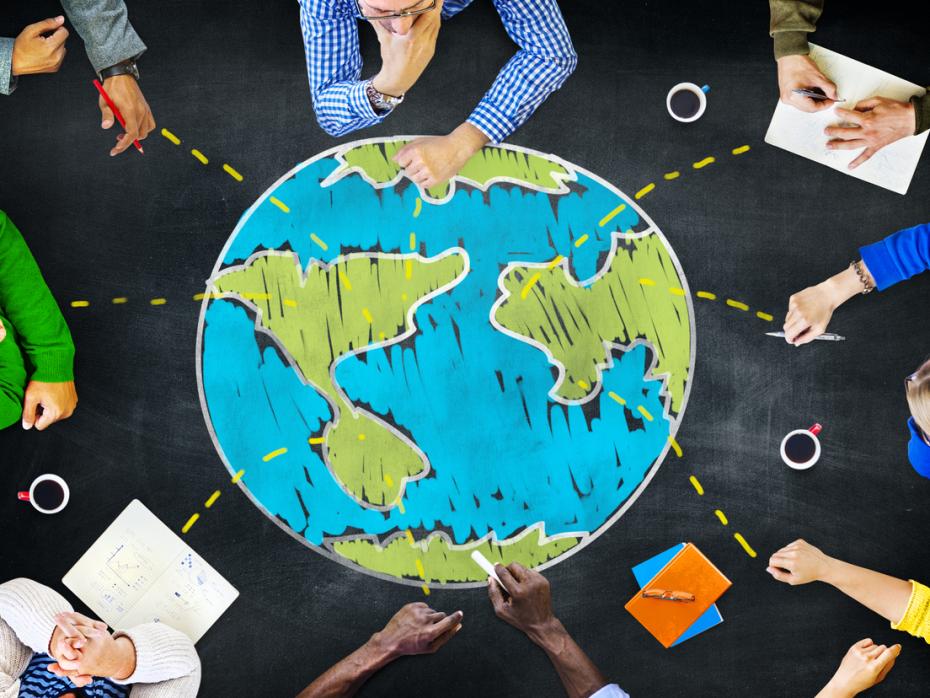 Top down view of people working on a table around an image of the globe