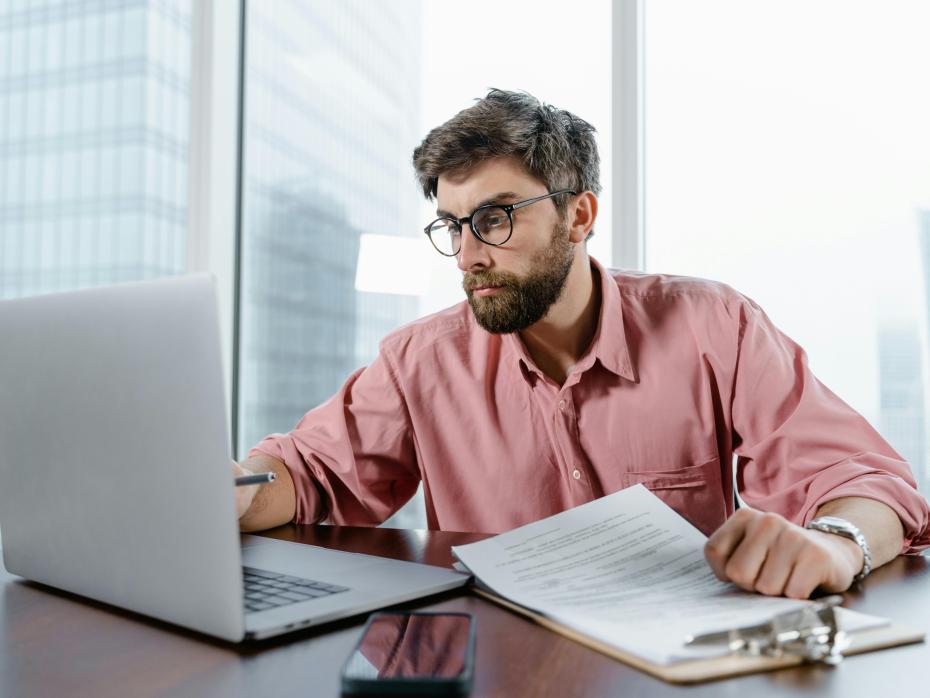 Man working on a laptop and taking notes