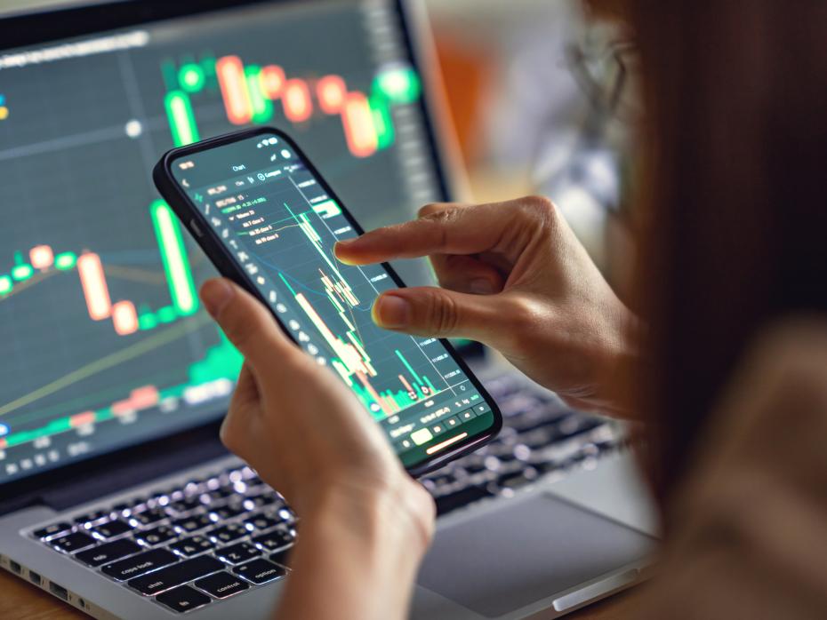 Woman checking Bitcoin price chart on digital exchange and smartphone