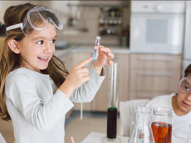 A small girl points to a test tube