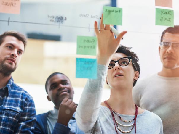 A team discusses at Post-It notes on a wall