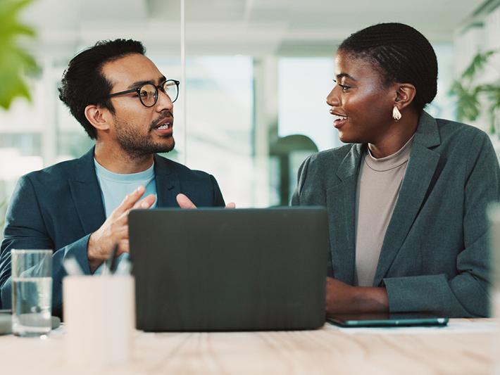 Two scholars discussing over laptop