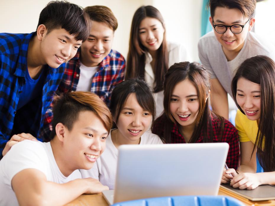 Chinese students crowding around a laptop in class