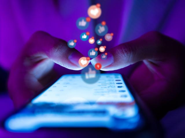 A pair of hands scroll social media on a smartphone