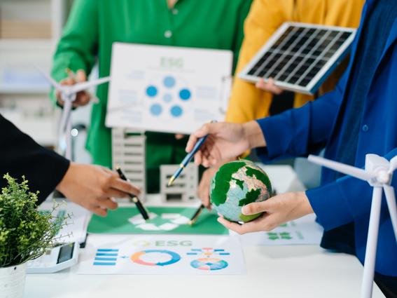 Students work with plants, a model of the Earth and a solar panel around a table