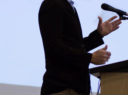 A lecturer stands in front of a microphone