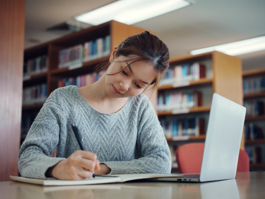 A university student taking notes by her laptop