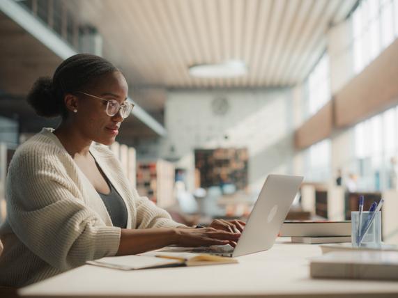 A young woman works at her laptop at the library