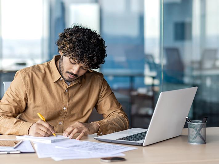 Young man working on document with laptop