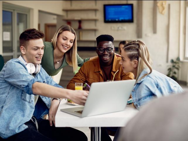 Students laugh around a laptop