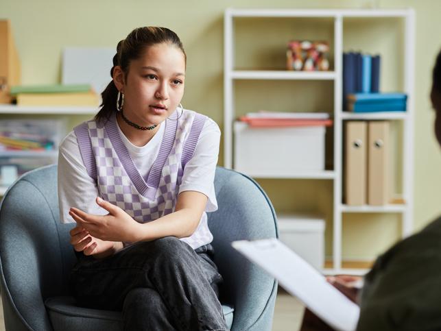 A student talks intently to an out-of-focus lecturer