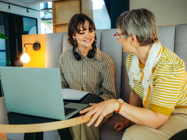 A mentor helps a student over a laptop