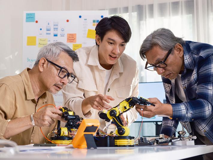 Three Asian men working on a robot