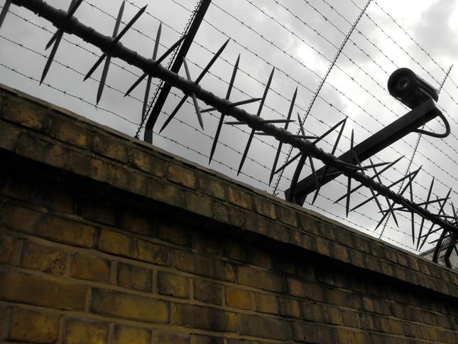 Barbed wire and a security camera on a brick wall