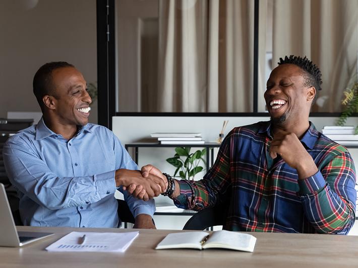 Two black men shaking hands and smiling