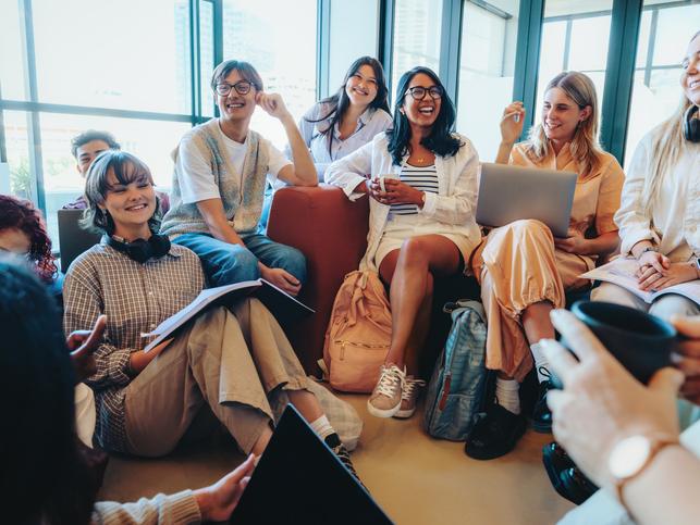 Students laugh together with a laptop