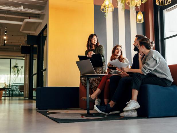 Educators chat on a sofa with a laptop