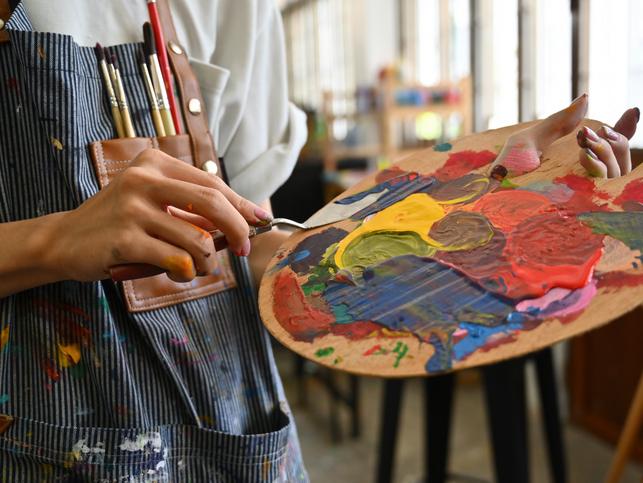 An artist mixes paints on a palette