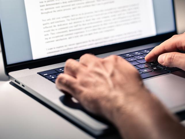 An academic works on a document on a laptop