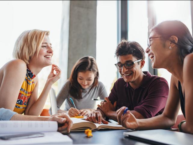Students laugh together over textbooks