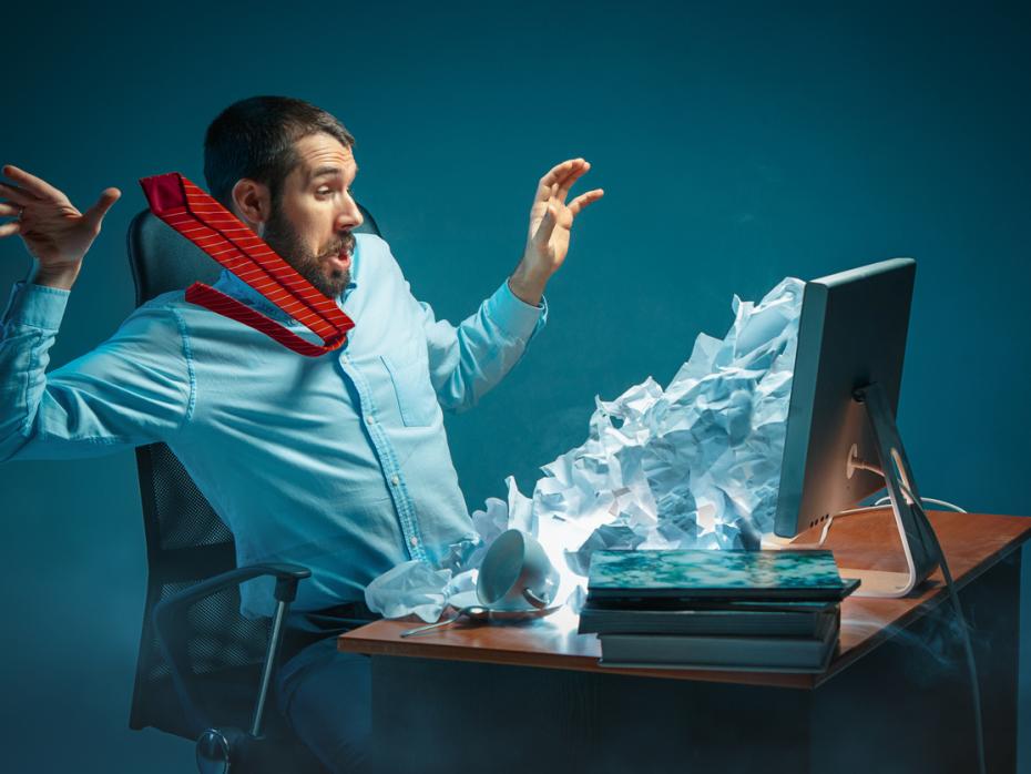 Young man looking stressed as his inbox explodes out of his screen