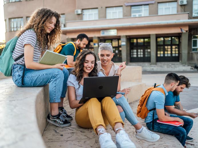 A group of students on campus using laptops and mobile devices