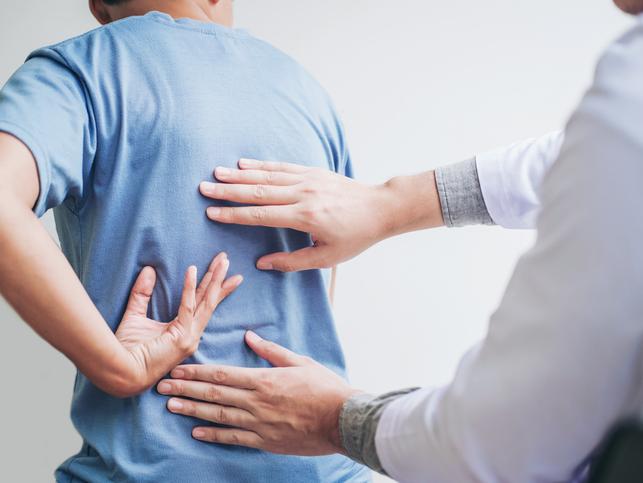 A physiotherapist inspects a patient's back