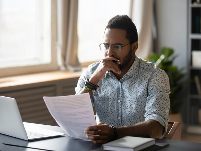 A man sitting at a laptop concentrates hard on a document