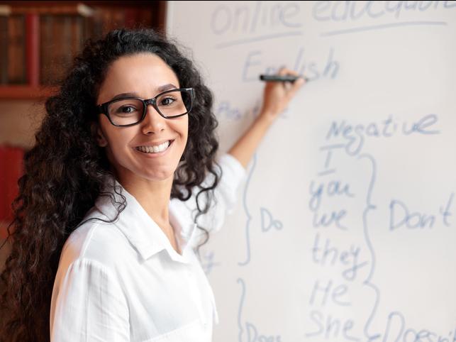 A teacher writes on a whiteboard