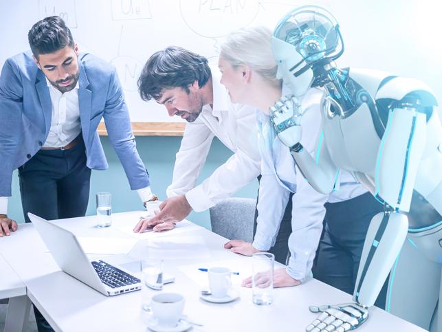 A robot leans over a meeting of humans