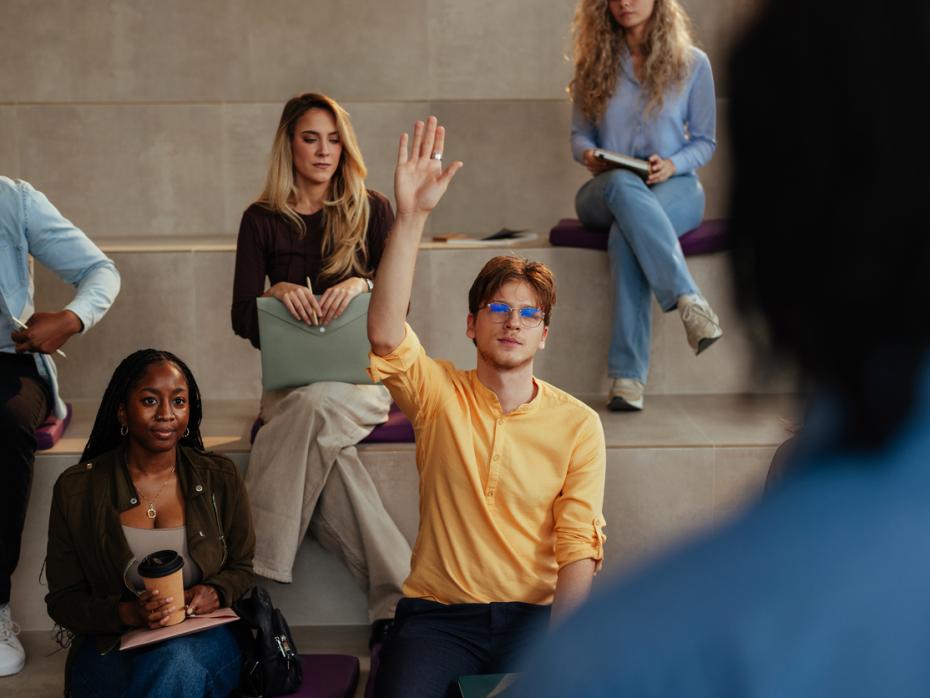 A student holding up his hand in class