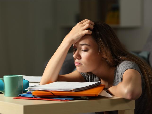 A student slumps over a pile of paperwork