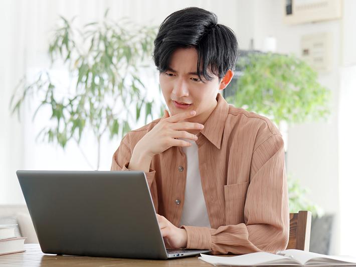Male Asian student working at laptop