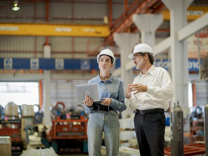 Young female engineer and older male colleague in a factory