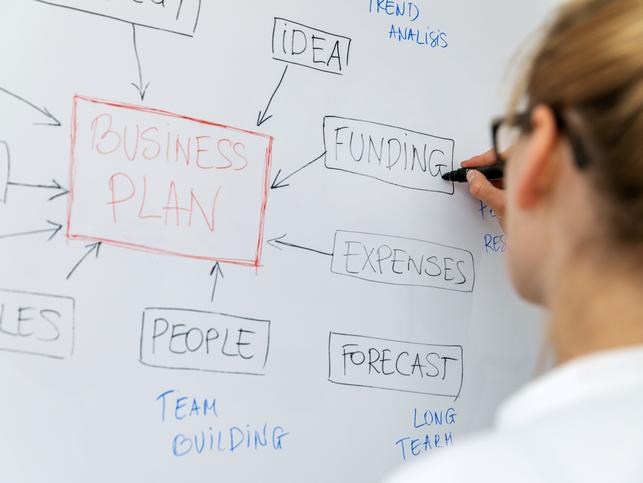 A woman starts her business plan on a whiteboard
