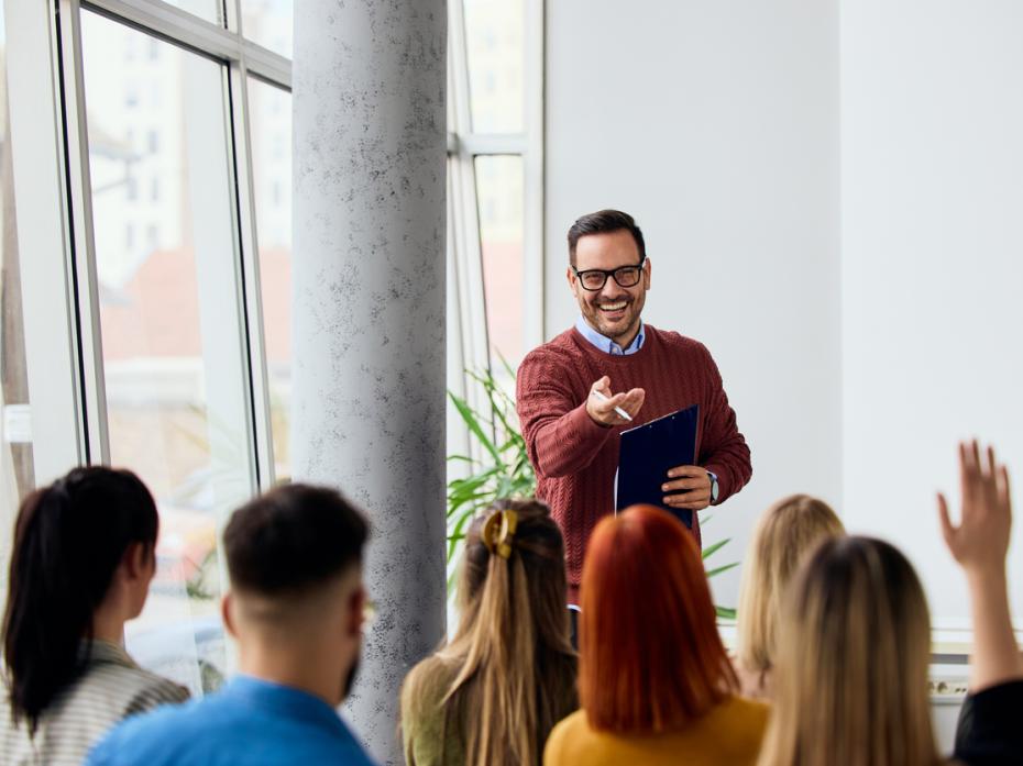 A teacher at the front of class interacting with a room full of students