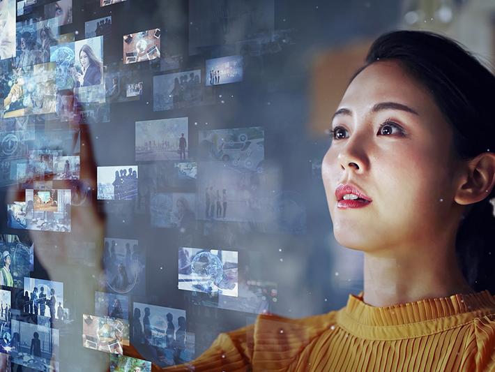 Young Asian woman looking at wall of electronic images