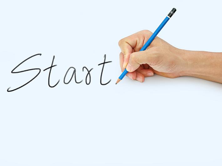 Start written on black page with hand holding a pencil