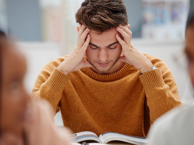 A student holds his head as he reads