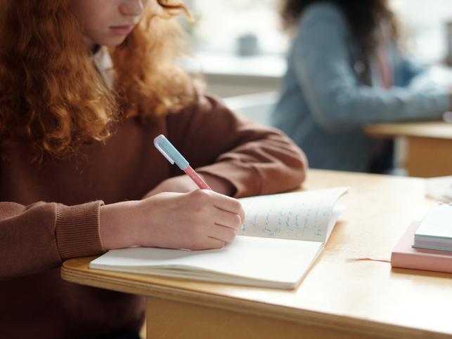 A student writes in a notebook
