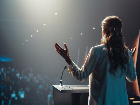 A woman speaks in front of an audience