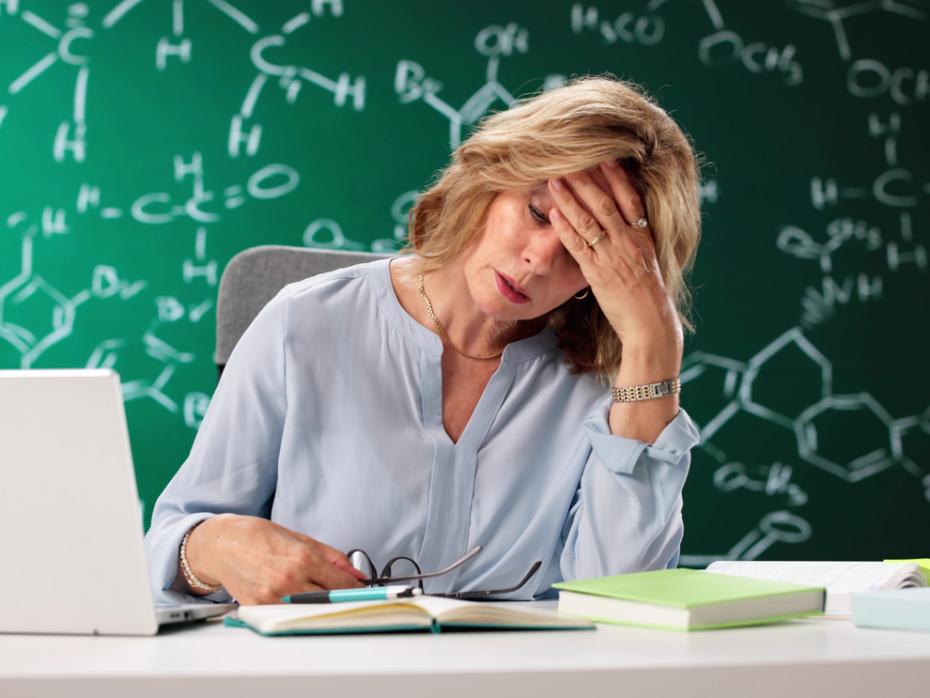 A female academic at her desk with her head in her hand