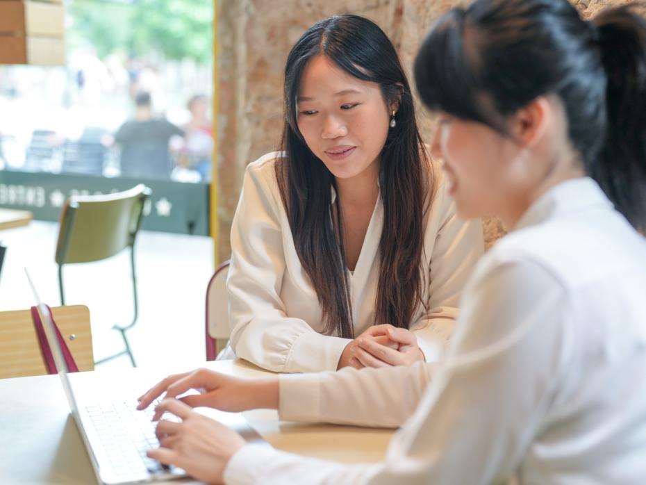 Two Chinese students working together on a latop