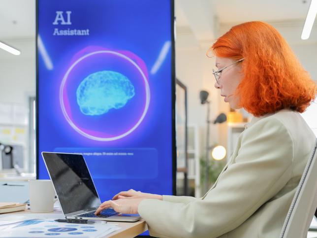 A woman works at a laptop in a library setting