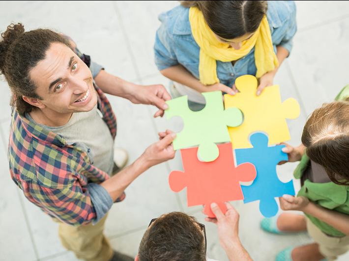 Group of young people holding jigsaw pieces, belonging concept
