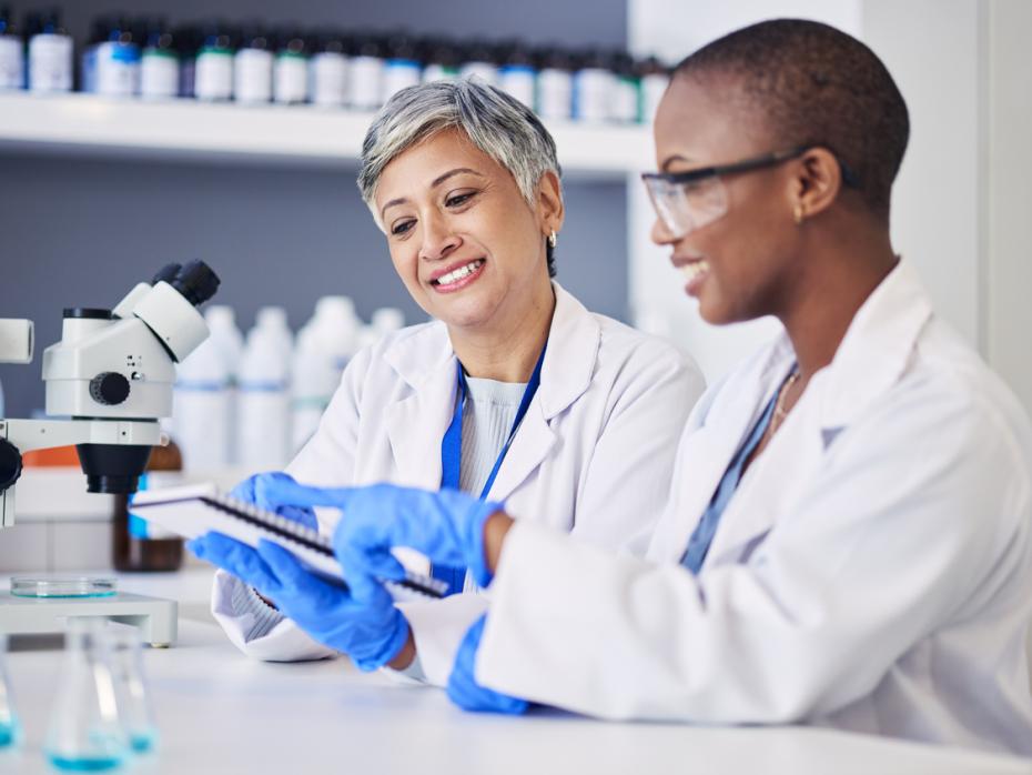 Two female scientists consulting a document in a lab