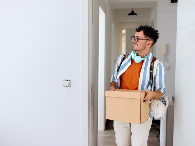 A new students arriving at his accommodation with a box of belongings