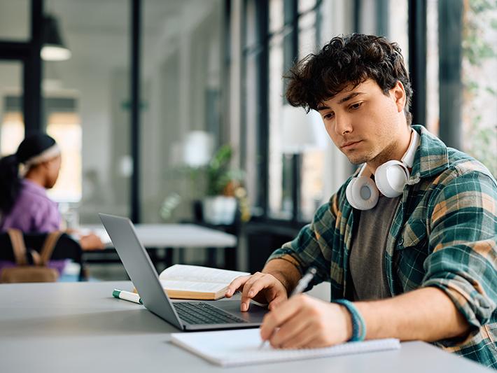 Young male college student studying in library